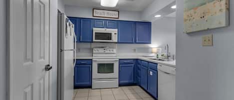 A kitchen with blue cabinets, a white refrigerator, a microwave, an oven, and a dishwasher.