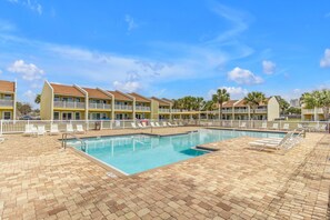 Un hotel con piscina, varios balcones y palmeras.