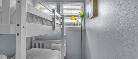Une chambre avec un lit superposé, une lampe sur pied et un tableau accroché au mur.