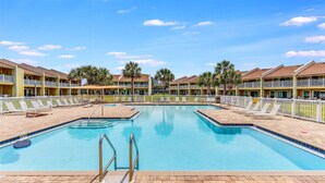 A swimming pool with a tiled deck, surrounded by a fence and palm trees. - 10D, The Beach Nest (Destin)