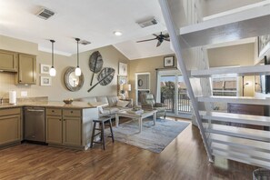 A spacious kitchen with wooden cabinets, a dining area with a sofa, and a staircase leading to an upper level. - 8G, Endless Summer (Destin)