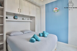 A bedroom with a bed, pillows, a wardrobe, and a wall with a circular artwork.