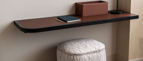 Una habitación moderna con un estante negro flotante que sostiene un libro, una lámpara y una caja marrón.
