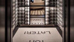 An elevator with a houndstooth patterned wall and a tiled floor with the word "LUXURY" visible.