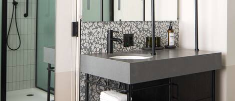 A modern bathroom with a large mirror, a sink, and a shower area.