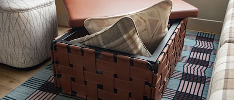 A wicker suitcase with a plaid cover placed on a patterned rug.