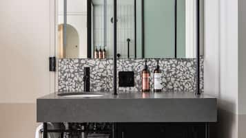 Une salle de bain moderne avec un meuble-lavabo noir, un miroir et un mur recouvert de carreaux.