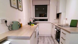 Een kleine keuken met een ingebouwde oven, een wasmachine en een raam boven de spoelbak.