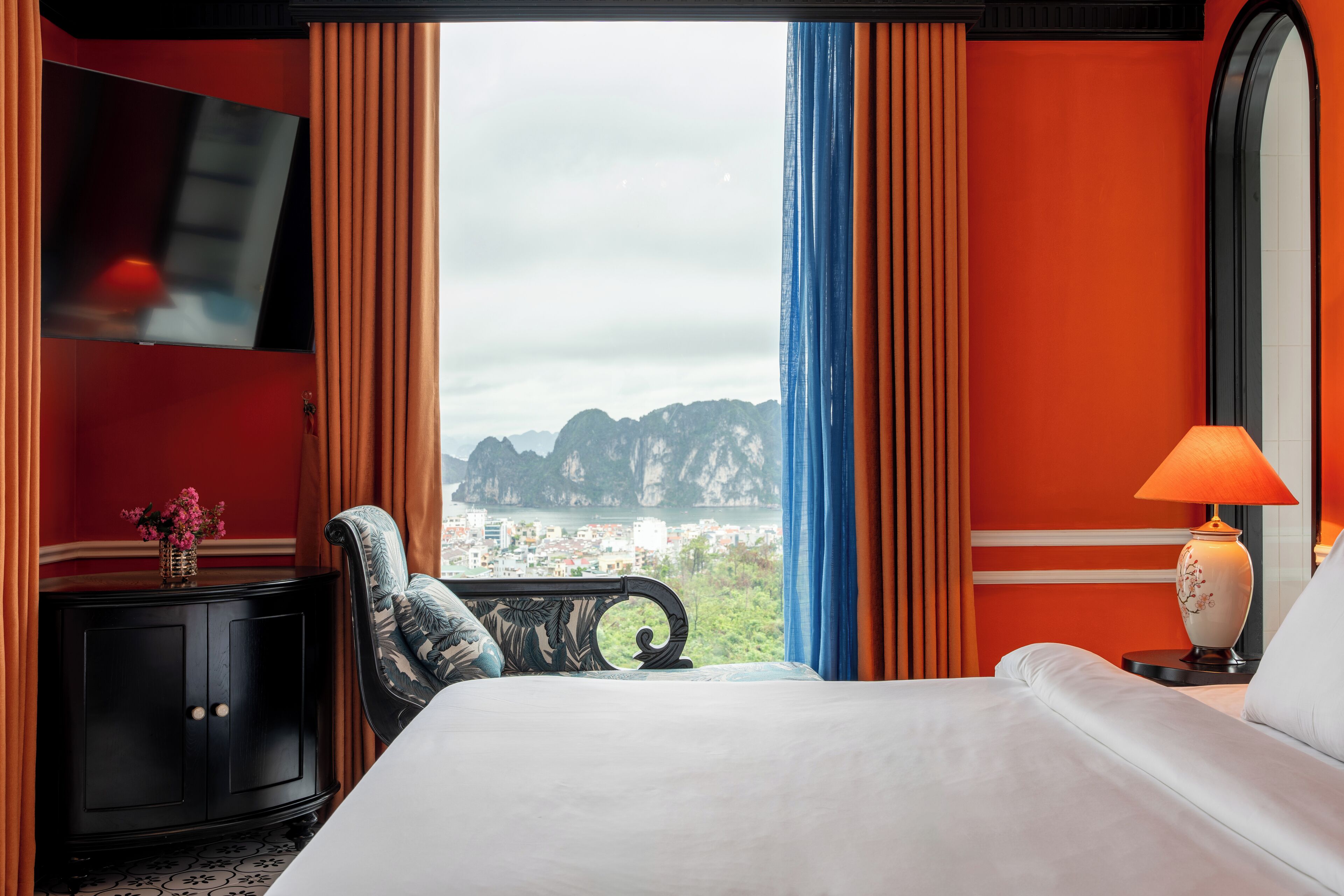 Una habitación de hotel con cama, televisor, escritorio y vistas a las montañas.