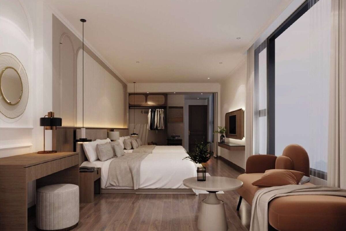 A modern hotel room with a large bed, a sitting area with a sofa, a small round table, and a large window.