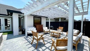 Une terrasse extérieure avec des meubles en bois, une pergola et un barbecue.