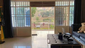 Een ruime woonkamer met een grote schuifpui naar een balkon, een bank, een salontafel en een laptop.