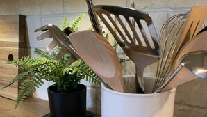 A kitchen counter with a utensil holder labeled "utensils," a small dish labeled "SPOON," and two salt shakers. - CHARMING...COMFORTABLE...CONVENIENT (Denton)