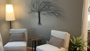 A living room with two armchairs, a small table, a lamp, and a wall-mounted tree decoration. - CHARMING...COMFORTABLE...CONVENIENT (Denton)