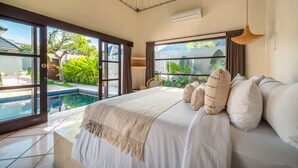 A bedroom with a large bed, a view of a swimming pool, and a ceiling fan. - Villa Panchajanya (Seminyak)