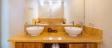 Un baño con dos lavamanos, un tocador de madera y un espejo.