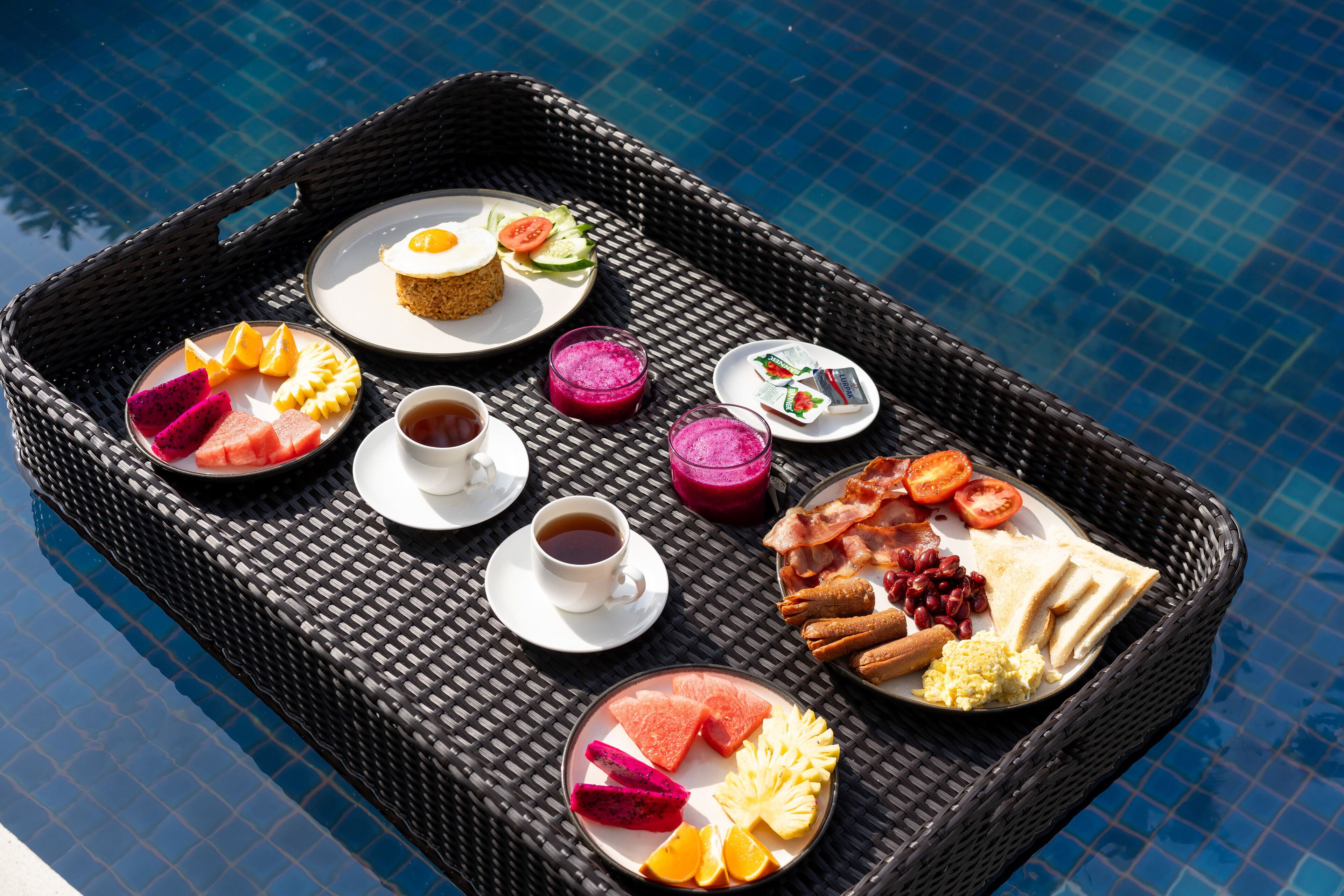 Ein Frühstückswagen mit verschiedenen Speisen und Getränken am Pool.