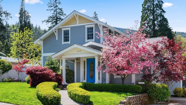 A two-story house with a blue front door, number 485, surrounded by well-maintained lawns and flowering trees. - The Ashland Social | Entire Estate (Ashland)