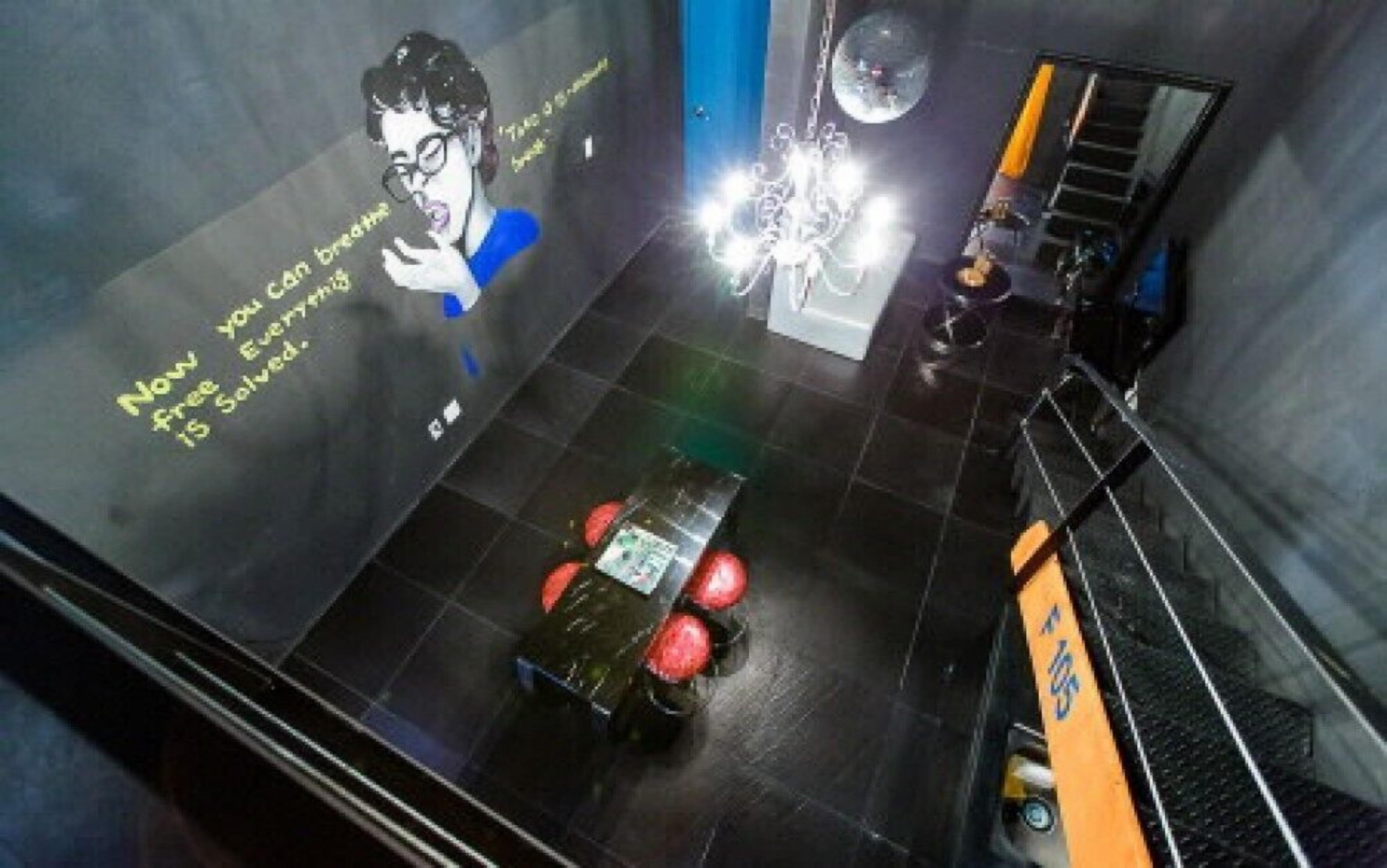 A modern interior with a black floor, a staircase, and a wall with a poster.