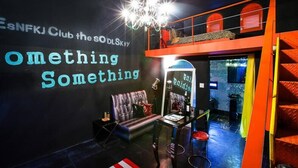 A lounge area with a sofa, a small table, and a chandelier. There is a sign on the wall that reads "something something." - Fapas Pension (Chuncheon)