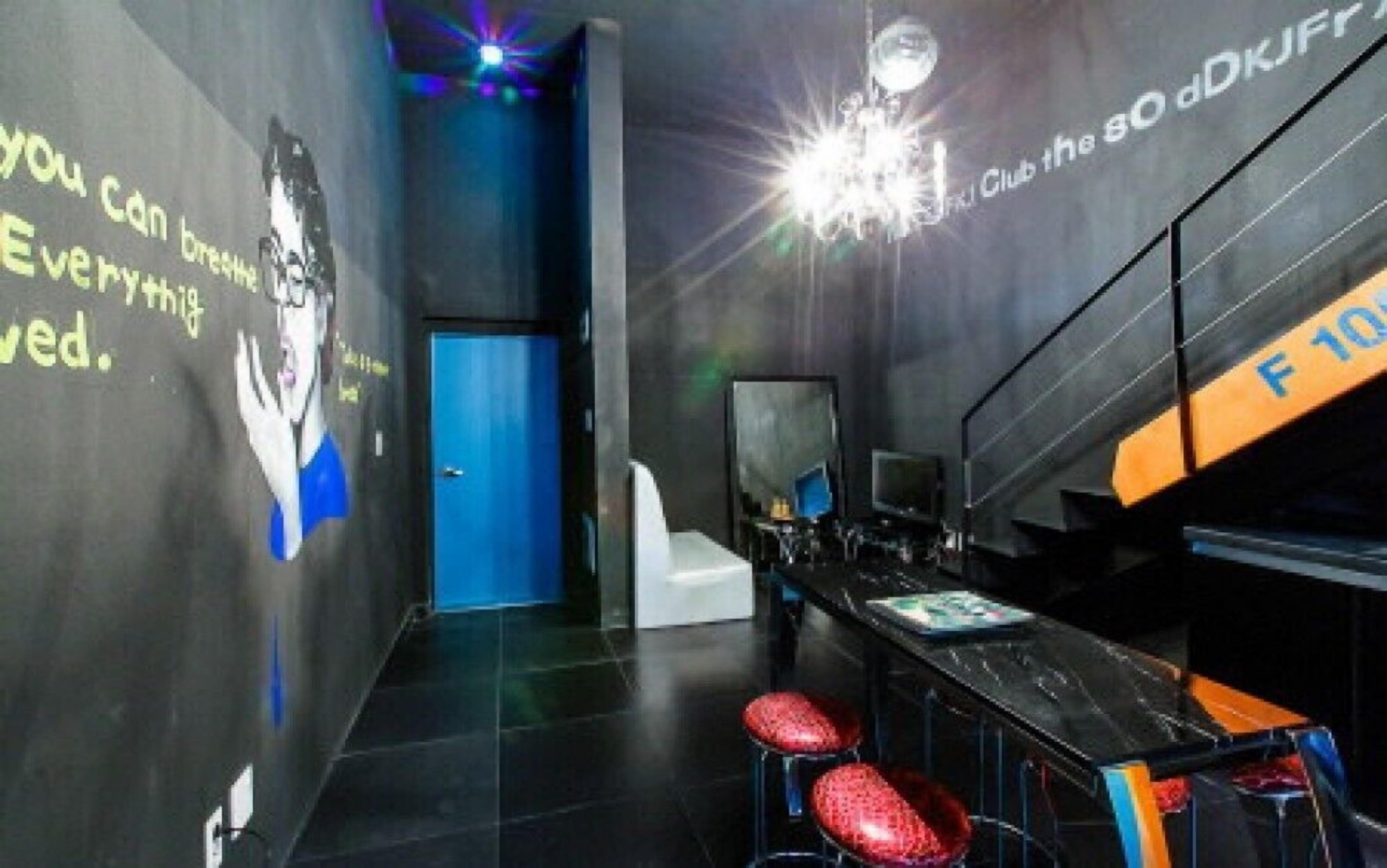A modern room with a dark floor, a blue door, and a bar area with stools and a counter.