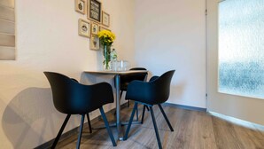 Un comedor con una mesa, sillas, un florero con flores y cuadros en la pared.
