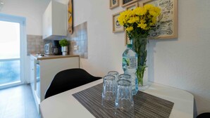 Una cocina con una mesa de comedor, un jarrón con flores amarillas y cuadros en la pared.