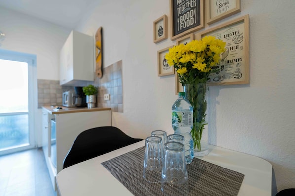 A kitchen with a dining table, a vase with yellow flowers, and framed pictures on the wall.