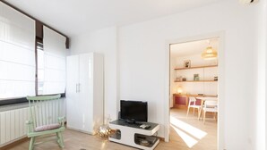 A modern living room with a television, a green chair, and a kitchen visible through an open door. - Via Marcona 17 Apartment (Milano)