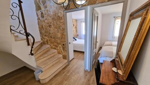 A staircase leading to a bedroom with a stone wall, a wooden floor, and a large mirror. - Mediterranean house with SEA VIEWS, garden and terrace. (Sant Feliu de Guíxols)