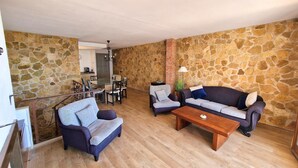A spacious living area with a stone wall, a wooden coffee table, two sofas, and a dining table with chairs. - Mediterranean house with SEA VIEWS, garden and terrace. (Sant Feliu de Guíxols)