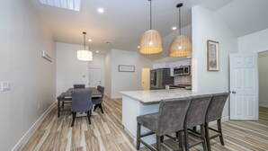 A modern kitchen with a central island, pendant lights, and a dining area with a table and chairs. - Casa flower centrally located  (Tucson)