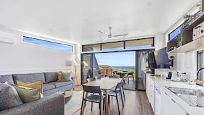 A modern kitchen with a large island, a dining area with a view, and a cozy seating area with a sofa and cushions. - Ingenia Holidays Cape Paterson (Cape Paterson)