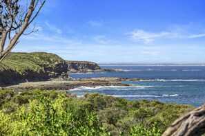 A coastal landscape with rocky cliffs, a clear blue sky, and the ocean. - Ingenia Holidays Cape Paterson (Cape Paterson)