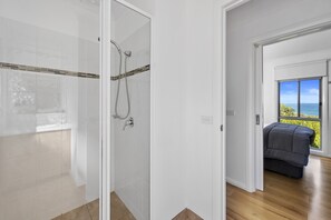 A modern bathroom with a glass shower enclosure, a visible towel rack, and a view of the ocean through an open door. - Ingenia Holidays Cape Paterson (Cape Paterson)