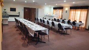 Un salón de conferencias con varias mesas dispuestas para comer, equipado con sillas y mesas.