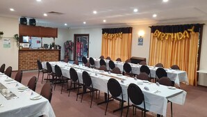 Un salón de conferencias con largas mesas, sillas y una zona de escenario.