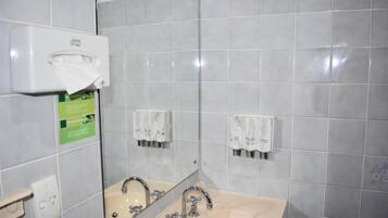 A bathroom with a sink, mirror, and two paper towel dispensers.