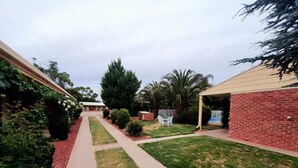 Un patio trasero residencial con un sendero pavimentado, césped y un edificio de ladrillo.