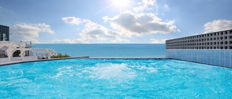 A swimming pool with a view of the ocean and a clear sky.