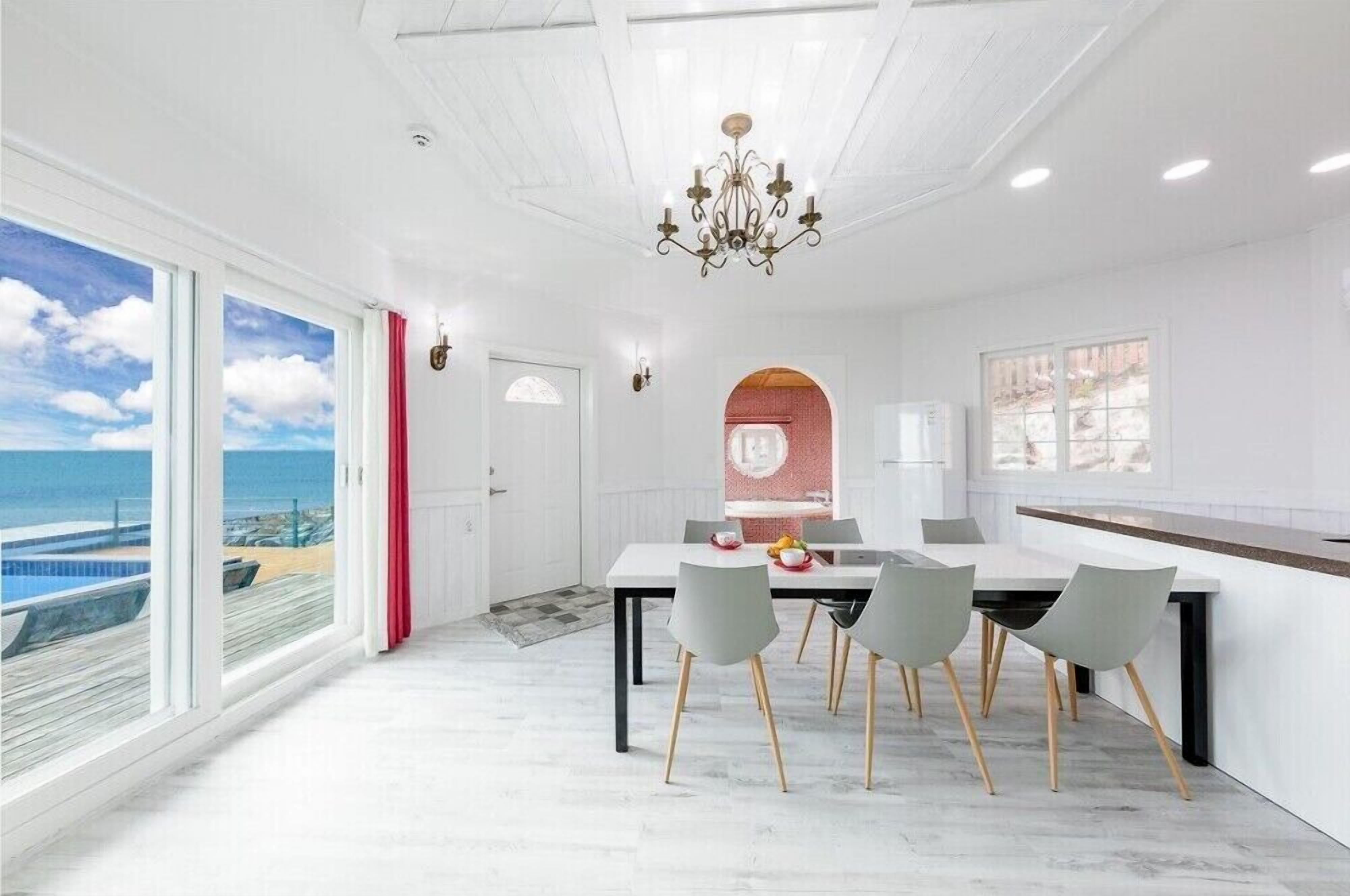 Un espace de restauration moderne avec vue sur l’océan, un lustre et une grande fenêtre.