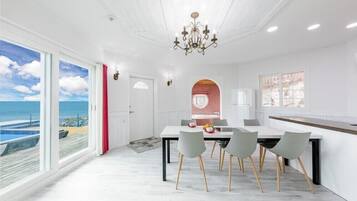 Un espace de restauration moderne avec vue sur l’océan, un lustre et une grande fenêtre.