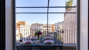 Un balcón con mesa lista para comer, con vista a un paisaje urbano.