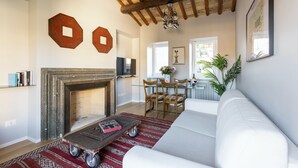 Una sala de estar con chimenea, un sofá, una mesa de centro y un comedor con sillas y una mesa.
