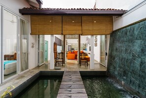A modern interior with a pool, a wooden deck, and a view into a living area with orange furniture. - An oasis in the city! (Sri Jayawardenepura Kotte)