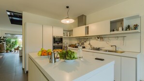 A modern kitchen with a central island, white cabinetry, and a hanging pot rack.