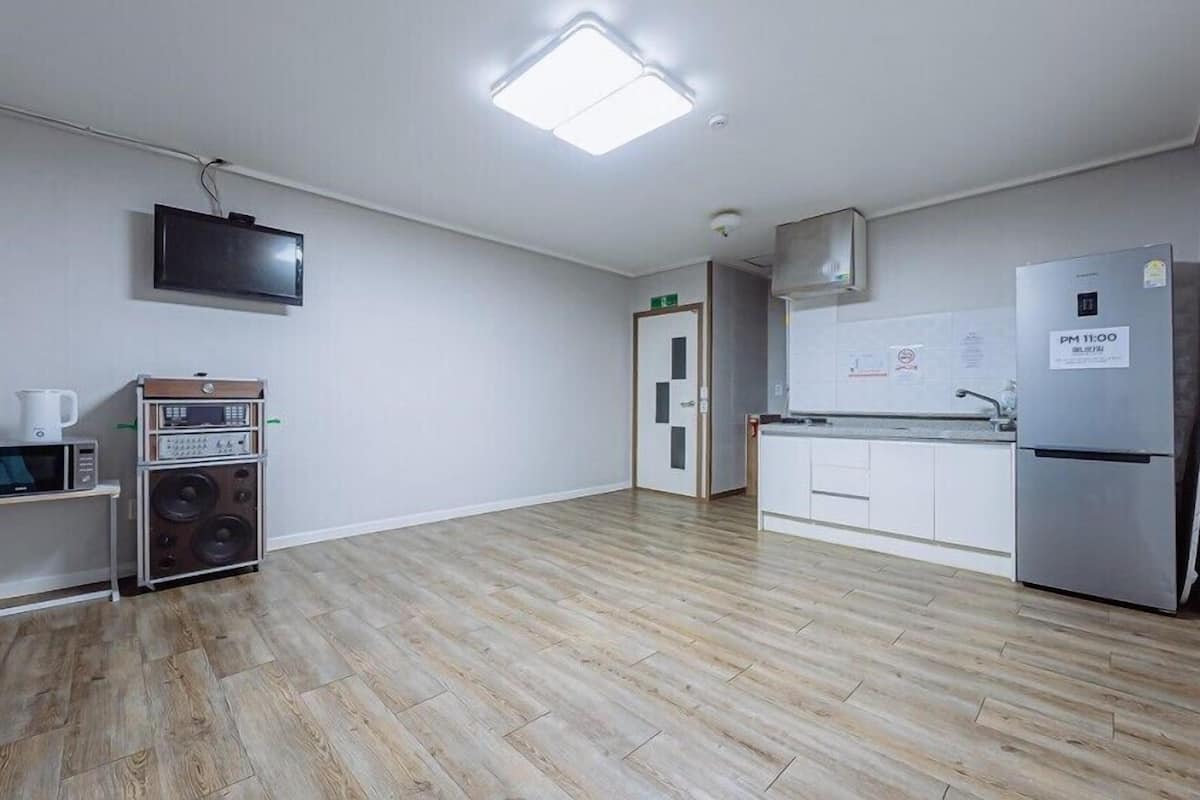 A modern kitchen with a flat-screen TV, a microwave, a coffee maker, and a refrigerator.