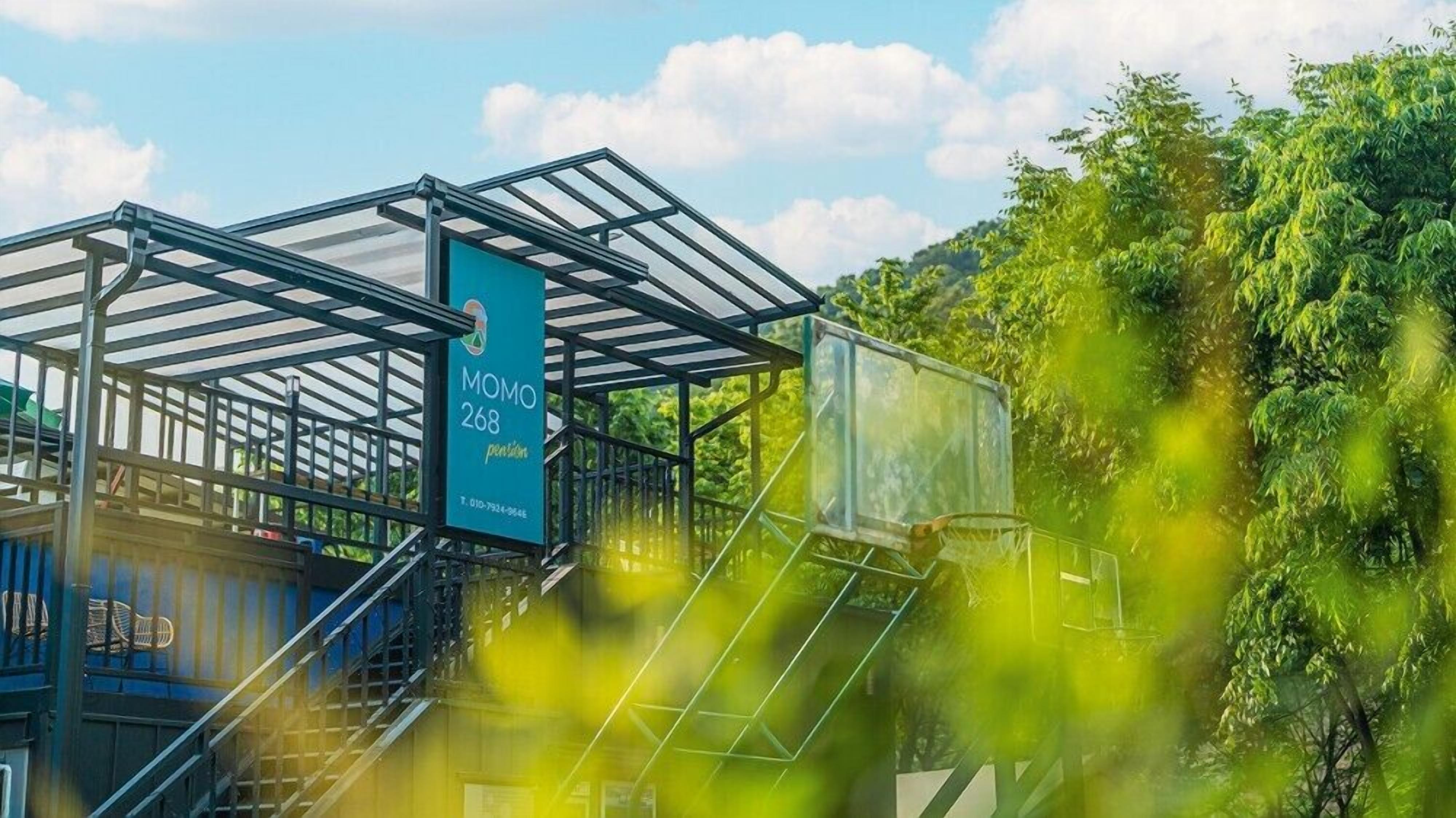 Een modern gebouw met een glazen gevel en een bord met de tekst 'MOMO 268'.