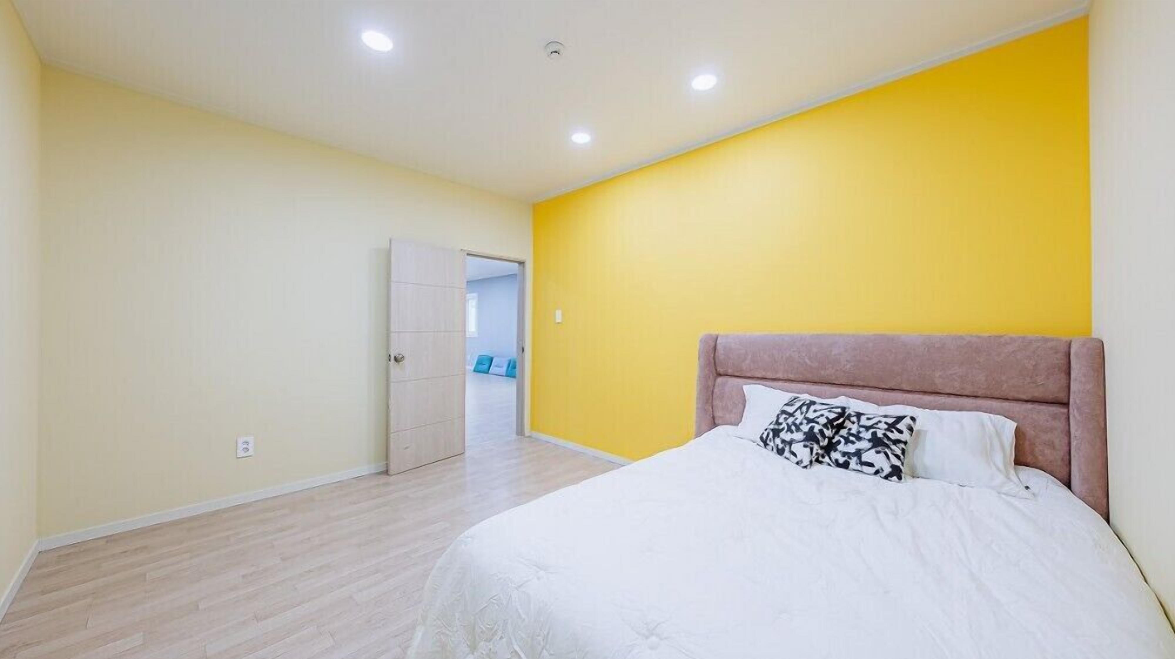 A bedroom with a bed, a door, and a yellow wall.