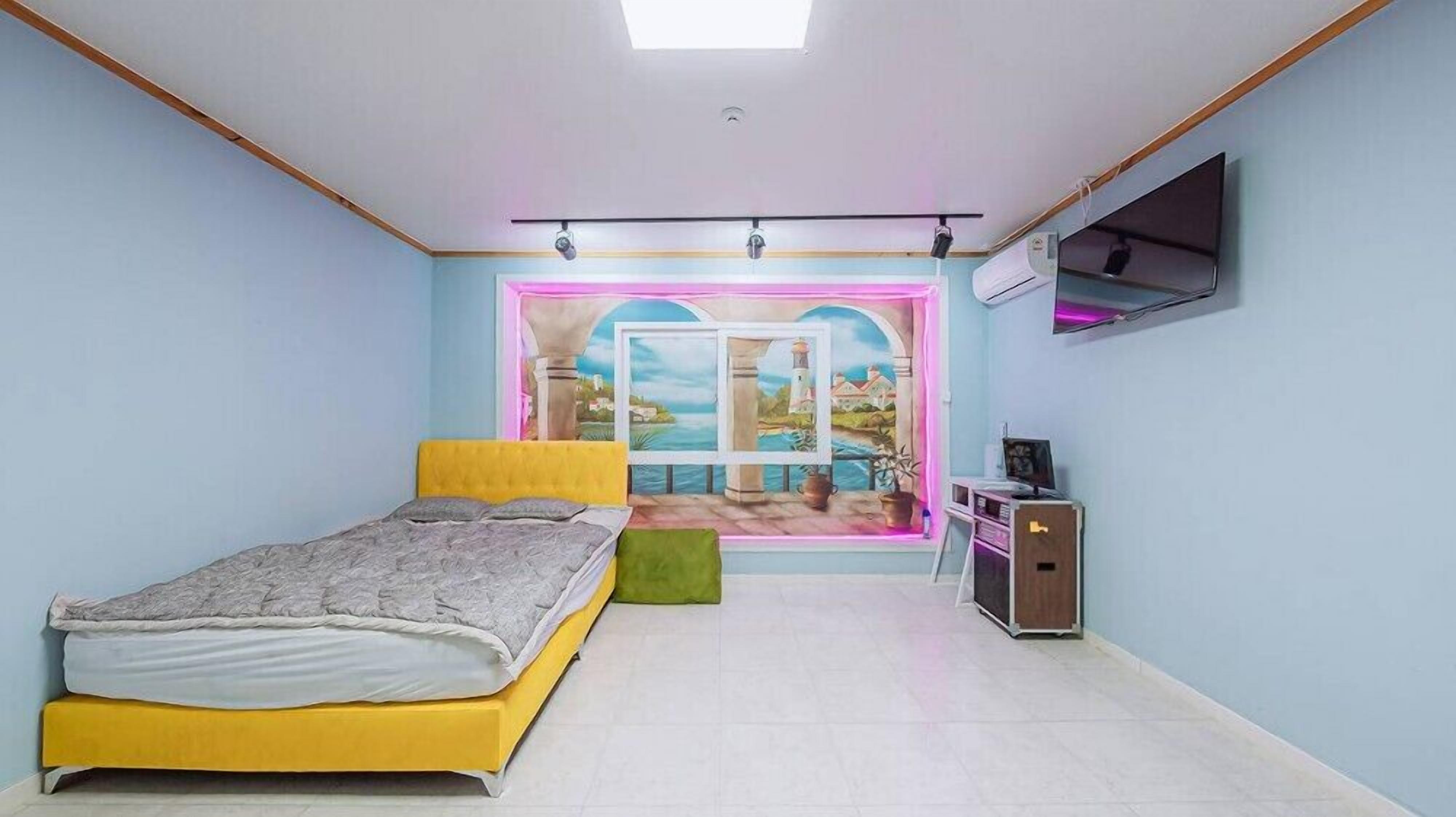 Un dormitorio con cama, televisión y ventana con vista a un paisaje.